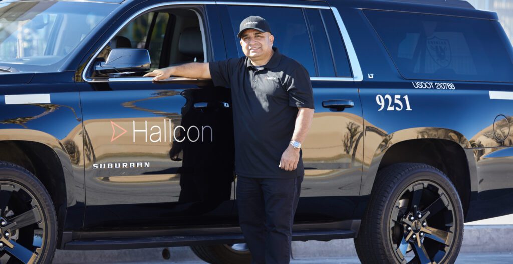 A Hallcon driver stands next to their Suburban SUV commuter vehicle.