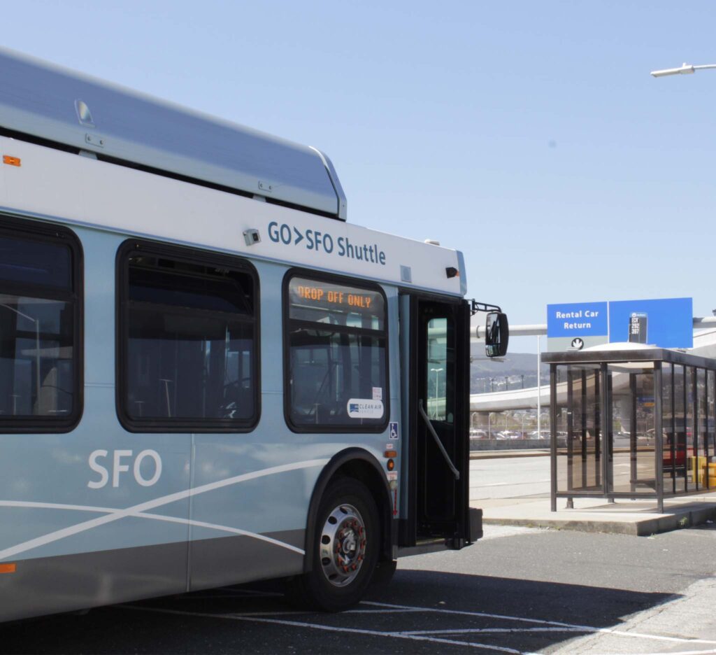 An SFO Bus facing a sign leading to a rental car facility.