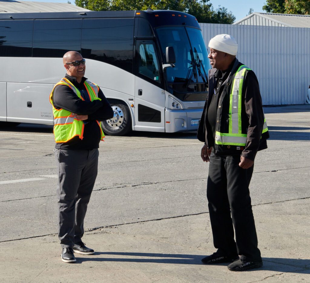 Two Hallcon team members chatting in front of a bus.