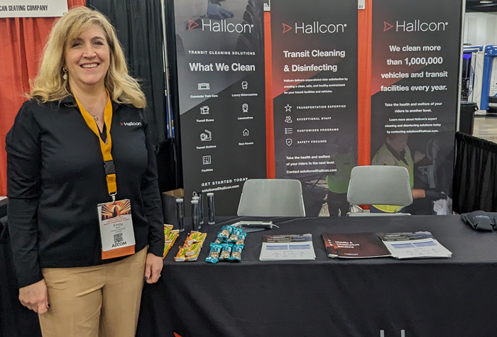 Emily Guill standing in front of Hallcon tradeshow booth.