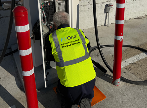 Hallcon employee working on an EV charger and wearing a neon yellow safety vest