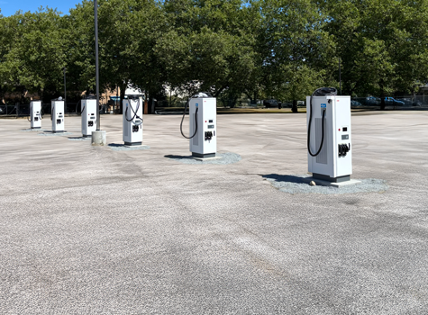 Several EV chargers lined up in a parking lot