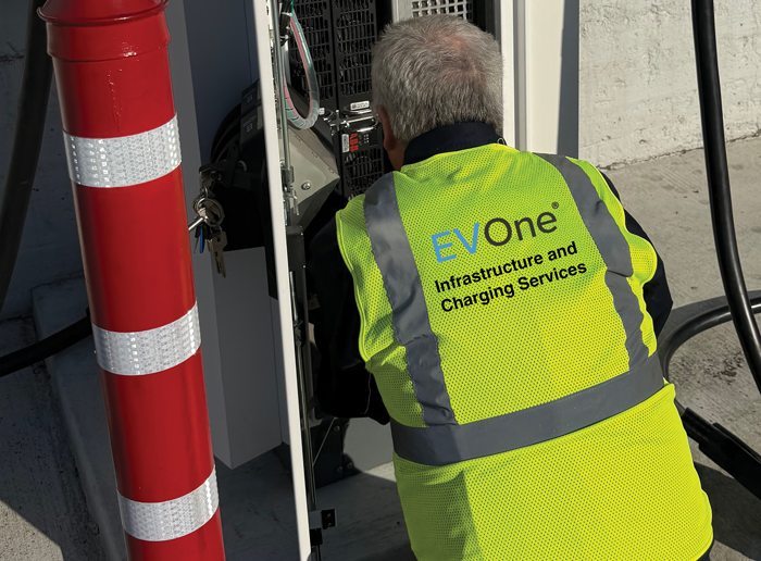 Back of an EV tech working on an EV charger
